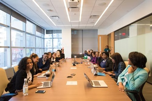 Grupo de personas reunidas en una mesa de conferencias en una oficina moderna con grandes ventanales