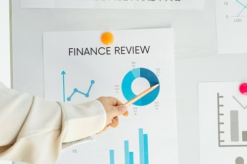 Persona señalando un tablero de revisión financiera en una pared