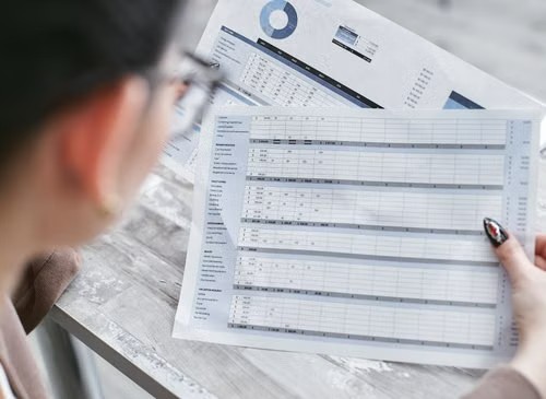 Persona revisando un documento financiero con tablas y gráficos