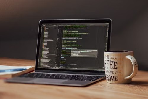 Laptop con código en pantalla sobre un escritorio de madera