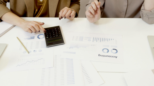 Manos revisando documentos contables y calculadora sobre la mesa